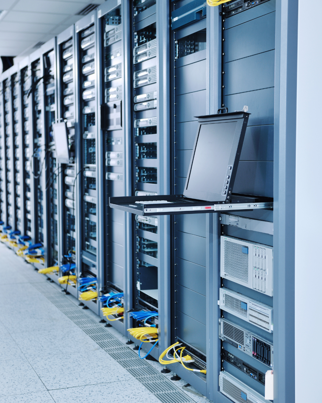 Rows of server racks in a data center with a pull-out monitor and keyboard tray